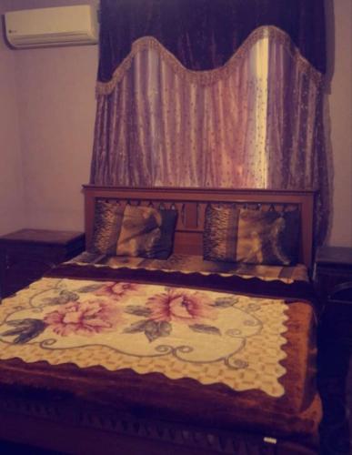 un lit avec une tête de lit en bois et un motif floral dans l'établissement شقق فندقيه مفروشه شامل الما الكهرباء, à Irbid