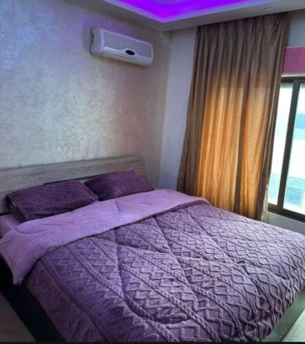 - une chambre avec un lit violet et une fenêtre dans l'établissement شقق فندقيه مفروشه شامل الما الكهرباء, à Irbid