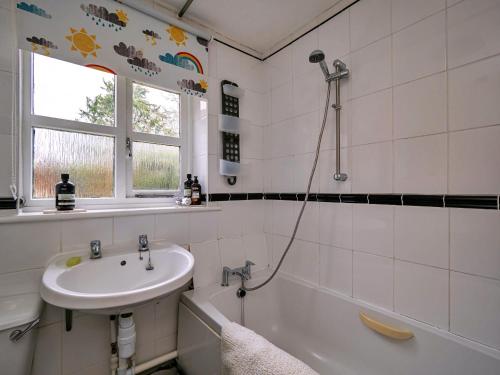 a white bathroom with a sink and a bath tub at Finest Retreats - Lychgate Cottage in Mattishall