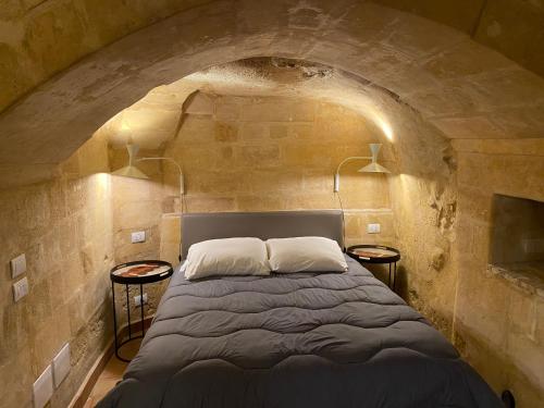 um quarto com uma cama numa parede de pedra em Suite San Biagio nei sassi em Matera