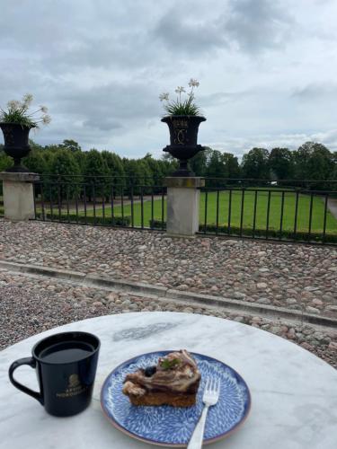 a plate of food on a table with a cup of coffee and a fork at Ett nytt fräsch hus utanför Stockholm nära Arlanda in Rosersberg