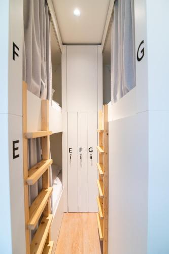 a room with white walls and wooden shelves at Azoriani City Hostel Ponta Delgada in Ponta Delgada