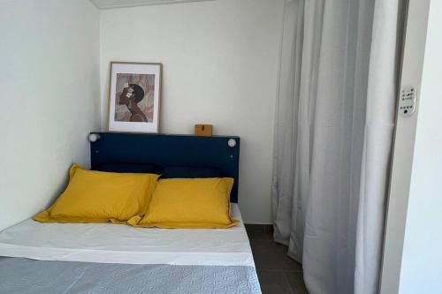 a bed with a blue headboard and yellow pillows at Le Pluméria - T1 avec un SPA privatif in Saint-Denis