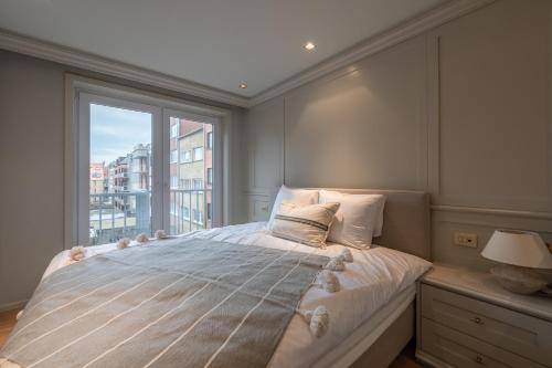um quarto com uma cama e uma janela grande em 3e verdiep Appartement op zeedijk in Knokke voor 7 personen em Knokke-Heist