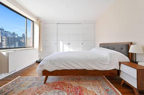 a white bedroom with a bed and a large window at Modern one bedroom with private balcony in New York