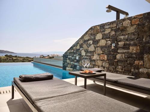 a room with a couch and a table next to a pool at Elounda Palm Hotel & Suites in Elounda