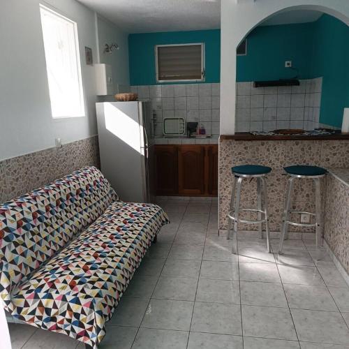 a kitchen with a couch in the middle of a room at Maison charmante au cœur de Le Gosier avec cheminée in Le Gosier