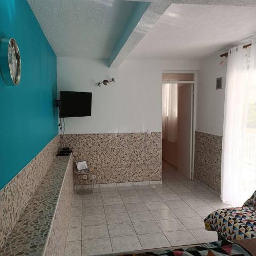 a room with a tv on the wall and a tile floor at Maison charmante au cœur de Le Gosier avec cheminée in Le Gosier