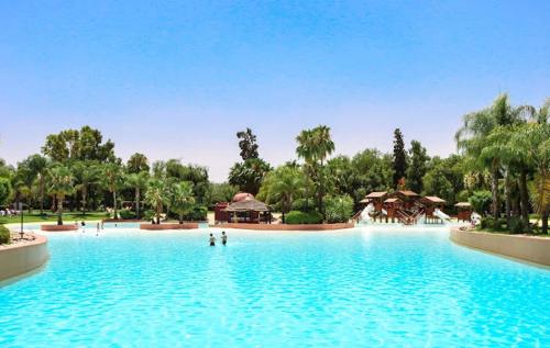 duży basen w parku z ludźmi w wodzie w obiekcie Villa de vos rêve w Marakeszu