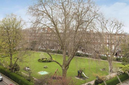 duży park z drzewem i placem zabaw w obiekcie Coronation Hotel w Londynie