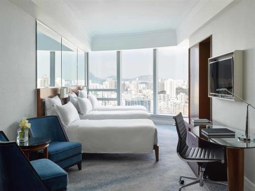 una camera d'albergo con un letto bianco e una grande finestra di Cordis, Hong Kong a Hong Kong