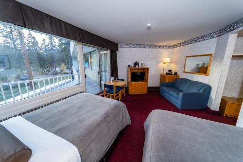 a hotel room with two beds and a chair and a window at Bow View Lodge in Banff