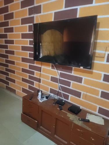 a brick wall with a tv on top of a dresser at Tobs home in Lagos