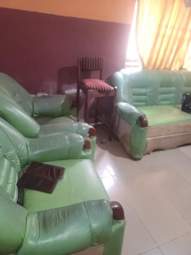 a living room with green chairs and couches at Tobs home in Lagos