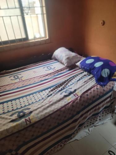uma cama com duas almofadas em cima em Tobs home em Lagos