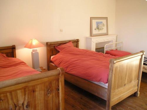 um quarto com 2 camas com lençóis vermelhos e um candeeiro em Maison de 3 chambres avec wifi a Fontenay sur Mer em Fontenay-sur-Mer