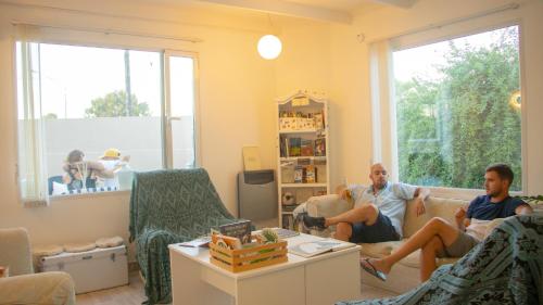 two men sitting in a living room playing a video game at Casa Amonite Hostel Boutique in Puerto Madryn