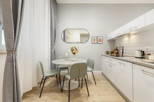cocina blanca con mesa, sillas y espejo en Homs Boutique Apartment, en Roma