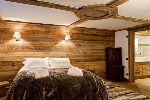 a bedroom with wooden walls and a bed with towels at Résidence Maison Du Praz - Maisons & Villas pour 8 Personnes 494 in Courchevel