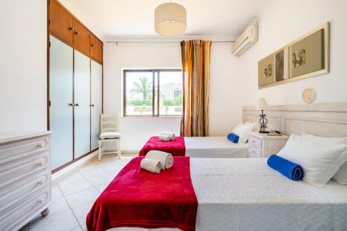 um quarto com 2 camas e um cobertor vermelho em Villa Palmeiras - Serene Private Villa em Albufeira