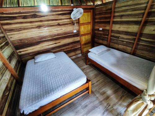 a room with two beds in a wooden cabin at Villa Esperanza in Palomino