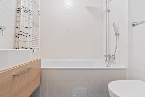 a white bathroom with a tub and a toilet at Designed Apt w Pool in Dommeldange in Luxembourg