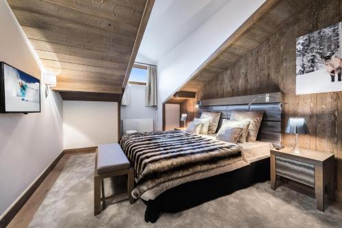 een slaapkamer met een groot bed en een houten muur bij Résidence Carre Blanc - 3 Pièces pour 4 Personnes 504 in Courchevel