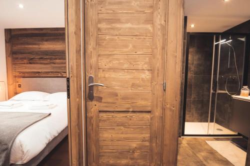 een houten deur in een slaapkamer met een bed en een douche bij Résidence Androsace Du Lyret - 2 Pièces pour 2 Personnes 564 in Chamonix-Mont-Blanc
