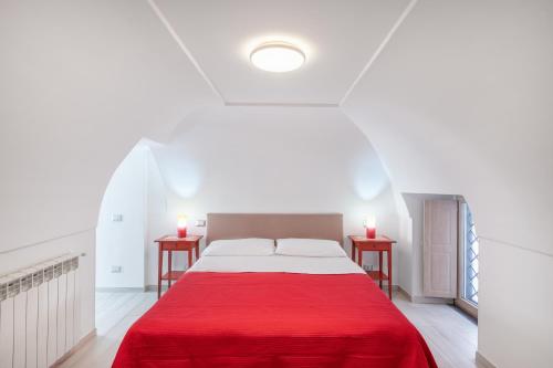 a white bedroom with a red bed with two tables at [Amalfi Coast]Elegant house in Penisola Sorrentina in Vico Equense