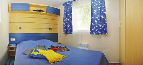 - une chambre avec un lit bleu et une fenêtre dans l'établissement Mobilhome 4 étoiles - Parc aquatique - eeia0f, au Bois-Plage-en-Ré
