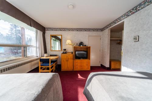 a hotel room with two beds and a television at Bow View Lodge in Banff