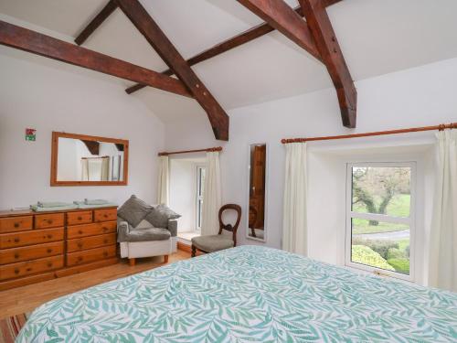 a bedroom with a bed and a dresser and a window at Pant in Llangranog