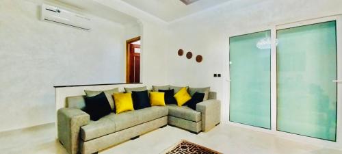 a living room with a couch with yellow pillows at Residence Al Kawtar in Mohammedia