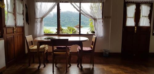 a dining room with a table and chairs and a window at Umah Tyang Pancasari in Bedugul