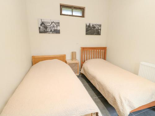 two twin beds in a room with a window at Coach House in Denbigh