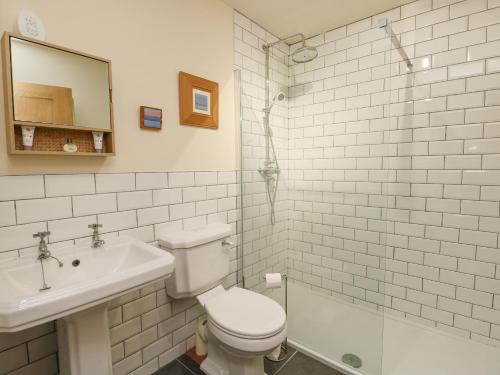 a white bathroom with a toilet and a sink at Coach House in Denbigh