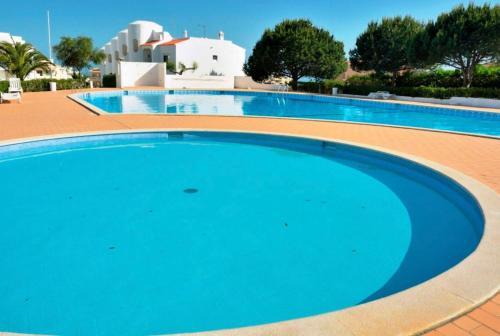 uma grande piscina azul com um edifício ao fundo em F&M - Quinta do Torrejão Alporchinhos Algarve em Porches