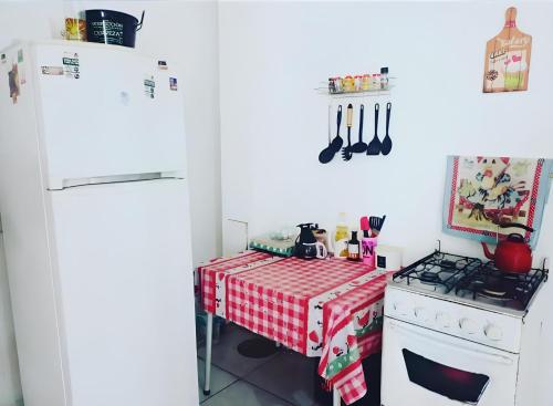 a kitchen with a table and a white refrigerator at Hostel Bahia in Porto Alegre