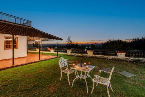 una mesa y sillas sentadas en un césped con puesta de sol en StayVista at The West Wind 5BHK Villa ooty comp Breakfast, en Ooty