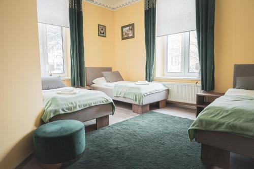 Cette chambre comprend deux lits, une chaise et deux fenêtres. dans l'établissement Mazurek - pokoje do wynajęcia, à Duszniki-Zdrój