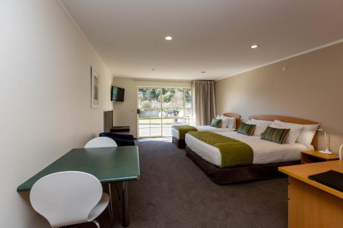 Habitación de hotel con 2 camas y escritorio en Aspen Court Motel Taihape en Taihape