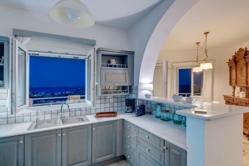a large kitchen with blue cabinets and a window at Villa la vue in Ano Syros