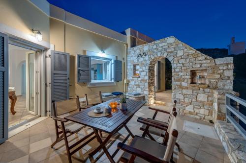 a patio with a table and chairs and a stone fireplace at Villa la vue in Ano Syros