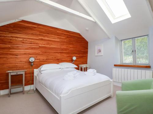 ニューキーにあるPilgrim Cottageの白いベッドと木製の壁が備わるベッドルーム1室が備わります。
