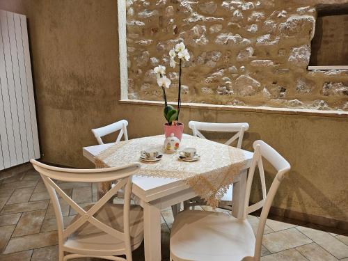 uma mesa branca com cadeiras e um vaso com flores em Agriturismo Il Raggio di sole di Orpello em Camerino