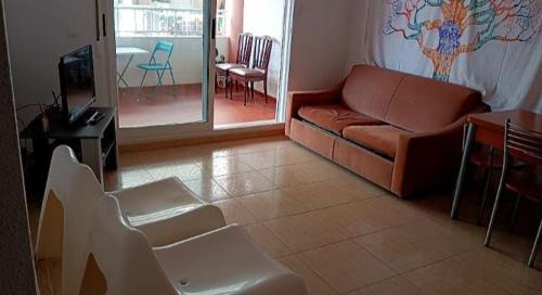een woonkamer met een bank en een tafel en stoelen bij habitacion en piso compartido cerca de playa in Xilxes