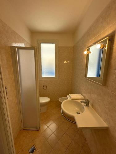 a bathroom with a sink and a toilet and a mirror at RESIDENCE STEFANIA Appartamenti piano terra - AGENZIA COCAL in Caorle