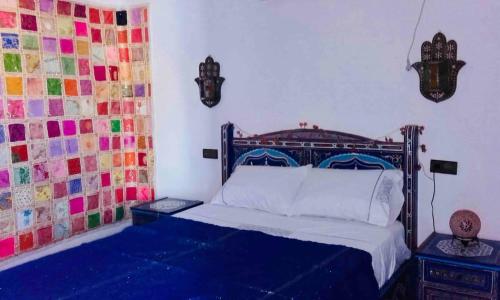 a bedroom with a bed with colorful tiles on the wall at Casa Azul in Chefchaouene