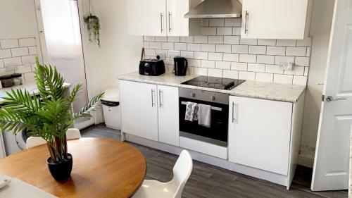 a kitchen with white cabinets and a wooden table at Herbert - MexTown Contractors in Mexborough