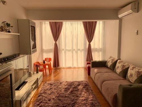 een woonkamer met een bank en een groot raam bij CozinessApart in Boekarest